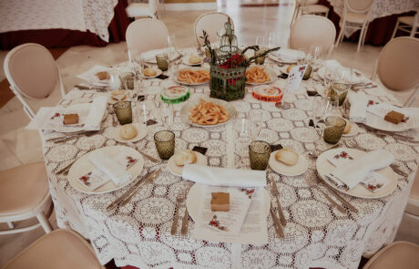 Montaje de mesas para banquete de boda con detalles florales y luces cálidas