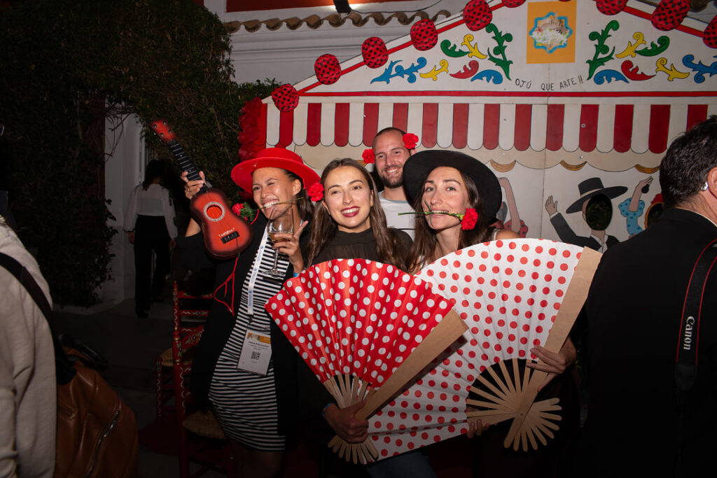 Montaje de cóctel al aire libre con mesas altas en jardín de hacienda azahares temática feria de abril